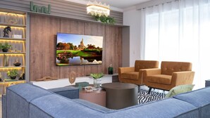 A modern living room with a large flat-screen TV, a chandelier, a sofa, and a coffee table.