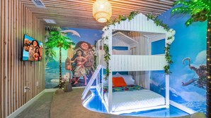 A room with a bunk bed, a TV, and a mural of a tropical scene.