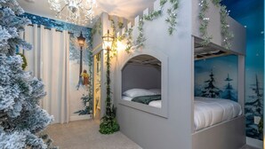 A cozy bedroom with a bunk bed, a decorative wall mural, and a Christmas tree. - House Resort at Encore Reunion - Disney (Kissimmee)
