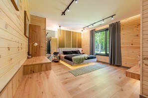 A modern bedroom with a wooden floor, a bed with a headboard, a bedside table, and a window with curtains. - Lakefront Mansion / Exclusive SPA, Fishing, Lake (Pocono Township)