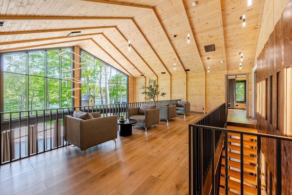 Une pièce spacieuse avec un plancher en bois, de grandes fenêtres et un escalier.