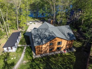 A modern two-story house with a large deck and a garage, surrounded by trees and a lake. - Lakefront Mansion / Exclusive SPA, Fishing, Lake (Pocono Township)