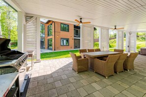 An outdoor patio with a grill, wicker furniture, and a view of a modern house. - Lakefront Mansion / Exclusive SPA, Fishing, Lake (Pocono Township)