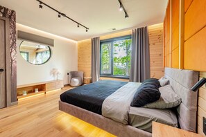 A modern bedroom with a large bed, a round mirror, a small chair, and a window with curtains. - Lakefront Mansion / Exclusive SPA, Fishing, Lake (Pocono Township)
