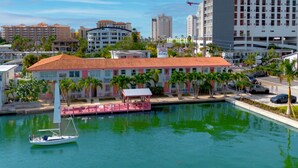 Un hotel frente al agua con un edificio de techo rojo, un muelle con un velero y un puerto deportivo.