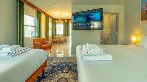 Habitación de hotel con dos camas, un comedor y un televisor que muestra servicios de streaming.