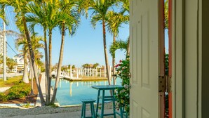 Zona de piscina con palmeras, una mesa y sillas.