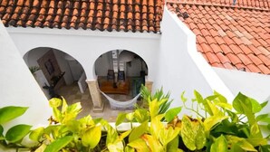 Ein Innenhof mit einem weißen Gebäude, einem roten Ziegeldach und einer Hängematte.