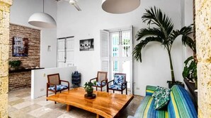 Ein geräumiges Zimmer mit einem Holztisch, zwei Stühlen, einer Couch und einer großen Topfpflanze.