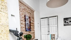 Eine Empfangshalle mit Backsteinwand, einer Engelsstatue, einer weißen Tür und einer Hängeleuchte.