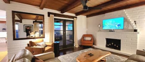 A modern living room with a wooden ceiling, a fireplace, a television, and leather sofas.