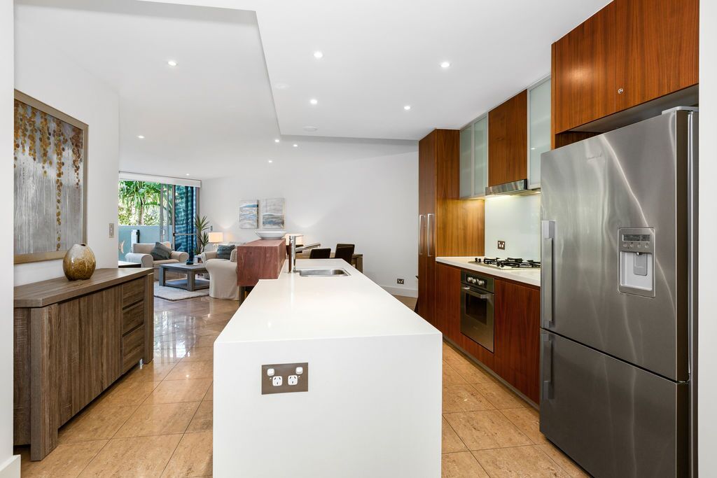 A modern kitchen with a central island, stainless steel appliances, and wooden cabinetry.