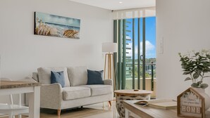A modern living room with a grey sofa, a small round table, and a painting on the wall. - Cotton Beach Resort (Casuarina)