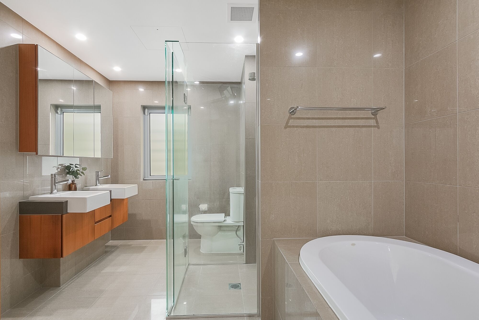 A modern bathroom with a glass-enclosed shower, a freestanding bathtub, and a dual sink vanity.