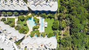 An aerial view of a resort with multiple buildings, a central swimming pool, and surrounding greenery. - Cotton Beach Resort (Casuarina)