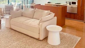 A modern living room with a beige sofa, a small white side table, and a ceiling fan. - Cotton Beach Resort (Casuarina)