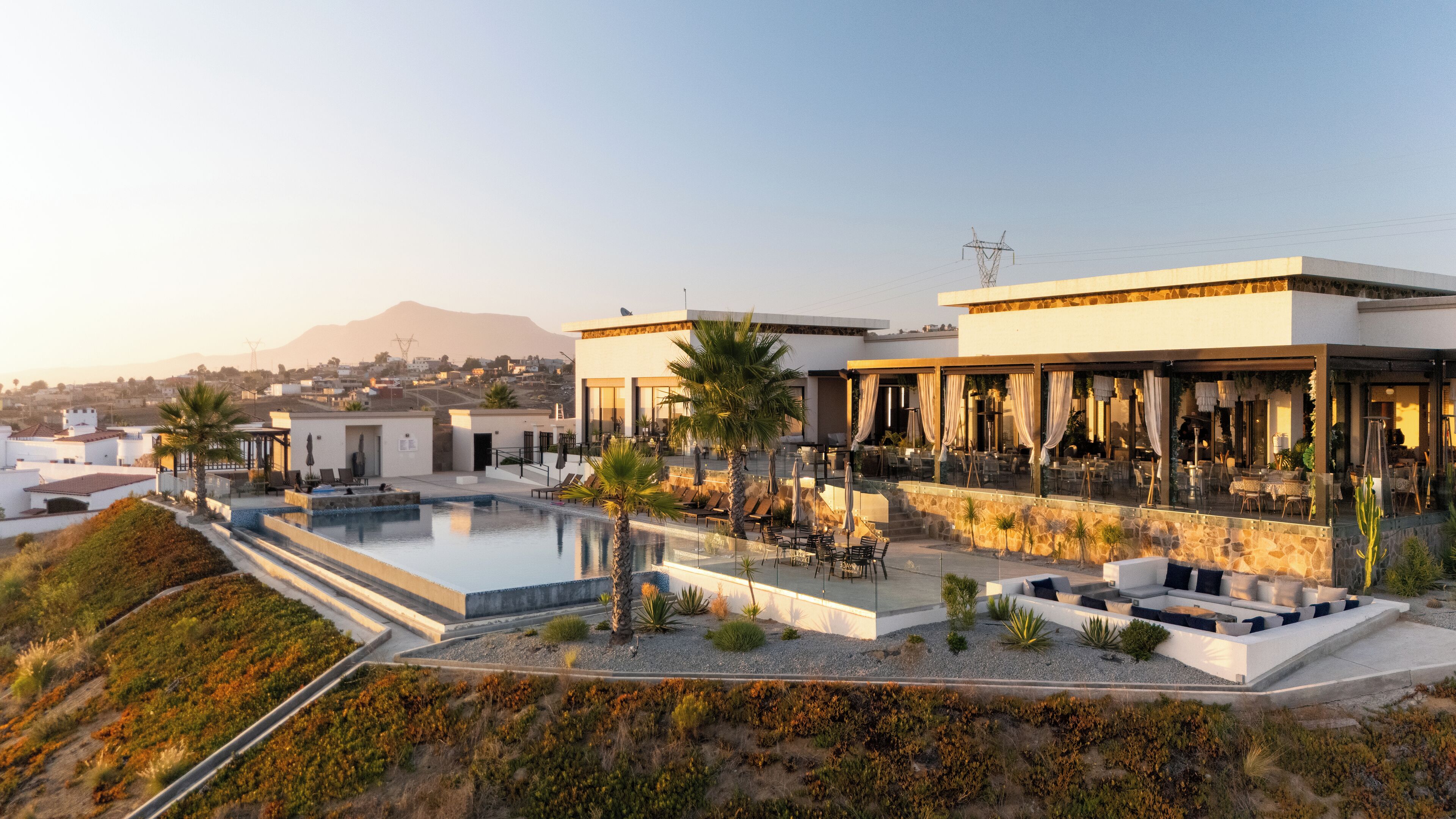 Un hotel moderno con piscina, zona de estar al aire libre y vistas del paisaje circundante.