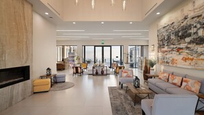 A spacious lobby with a fireplace, seating areas, and a large abstract painting on the wall. - Voyage Vacation Club (Playas de Rosarito)