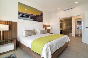 A modern hotel room with a large bed, a wooden headboard, and a painting of a sunset over the ocean.