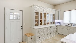 A kitchen with white cabinetry, a wooden bench, and a marble countertop.