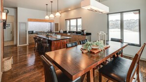 A spacious kitchen with a large island, wooden flooring, and pendant lighting.