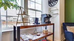 Une pièce chaleureuse avec une table basse en bois, un fauteuil bleu et une vue sur l’extérieur grâce à une grande fenêtre.