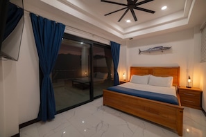 Un dormitorio con cama, mesita de noche, ventilador de techo y una decoración de peces en la pared.