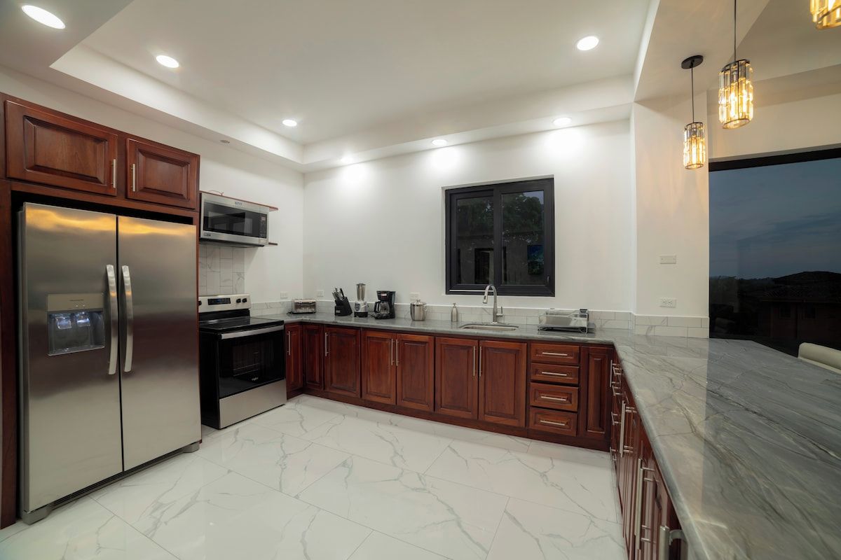 A modern kitchen with stainless steel appliances, wooden cabinets, and a marble countertop.