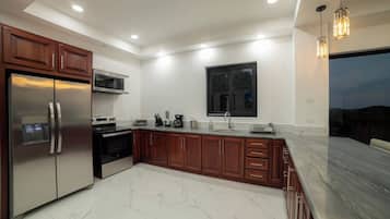A modern kitchen with stainless steel appliances, wooden cabinets, and a marble countertop.