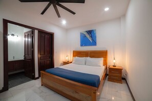 Un dormitorio con cama de madera, mesitas de noche, ventilador de techo y un cuadro colgado en la pared.
