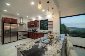 Una cocina moderna con electrodomésticos de acero inoxidable, una isla grande e iluminación colgante.