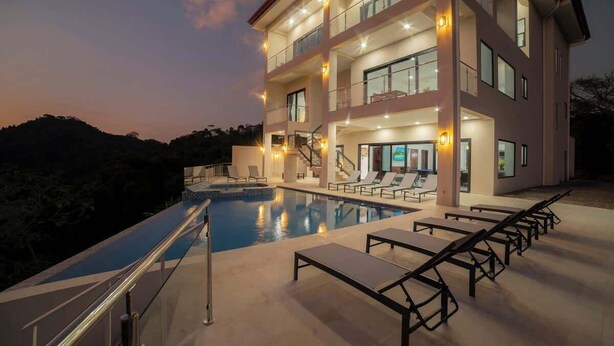 Un hotel de varios pisos con piscina, mobiliario exterior y vistas del paisaje circundante.