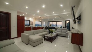 Amplia sala de estar con un sofá seccional, una mesa de centro y un televisor montado en la pared.