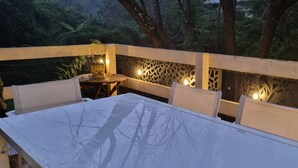 An outdoor patio with a white table and chairs, a decorative wall with lights, and a view of trees in the background. - Idyllwylde: pet-friendly, renovated vintage  cabin, close to town and river (Warburton)