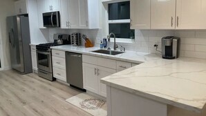A modern kitchen with white cabinets, stainless steel appliances, and a marble countertop. - Bremerton Retreat-30 min Fast Ferry to Seattle-Pet Friendly (Bremerton)