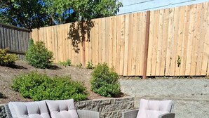 An outdoor seating area with wicker furniture and a glass-top coffee table, surrounded by a patterned rug. - Bremerton Retreat-30 min Fast Ferry to Seattle-Pet Friendly (Bremerton)