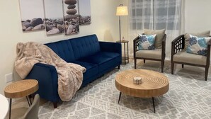 A living room with a blue sofa, a round wooden coffee table, and two armchairs with patterned cushions. - Bremerton Retreat-30 min Fast Ferry to Seattle-Pet Friendly (Bremerton)