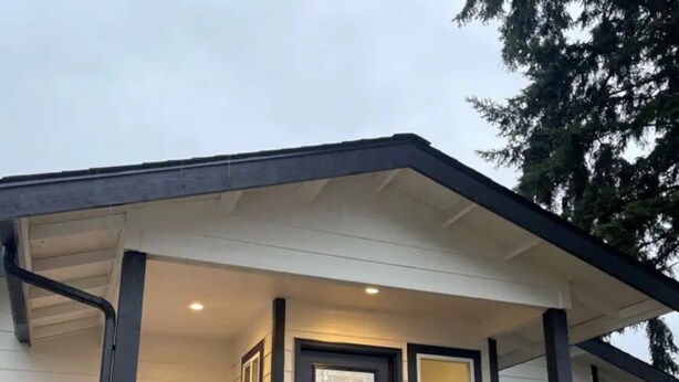 A single-story house with a dark front door, a small porch with a wooden railing, and a visible garage door. - Bremerton Retreat-30 min Fast Ferry to Seattle-Pet Friendly (Bremerton)