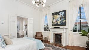 Un dormitorio amplio con una cama grande, una chimenea y vistas de la ciudad a través de amplias ventanas.