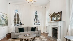 Una sala de estar con un sofá seccional color beige, una mesa de centro redonda de madera y una chimenea.