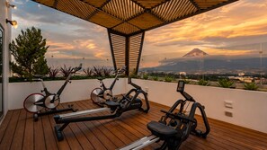 A rooftop gym with exercise equipment and a view of a mountain.