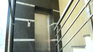 An elevator in a building with a metallic finish and a control panel on the wall. - Hotel MN Grand (Hyderabad)