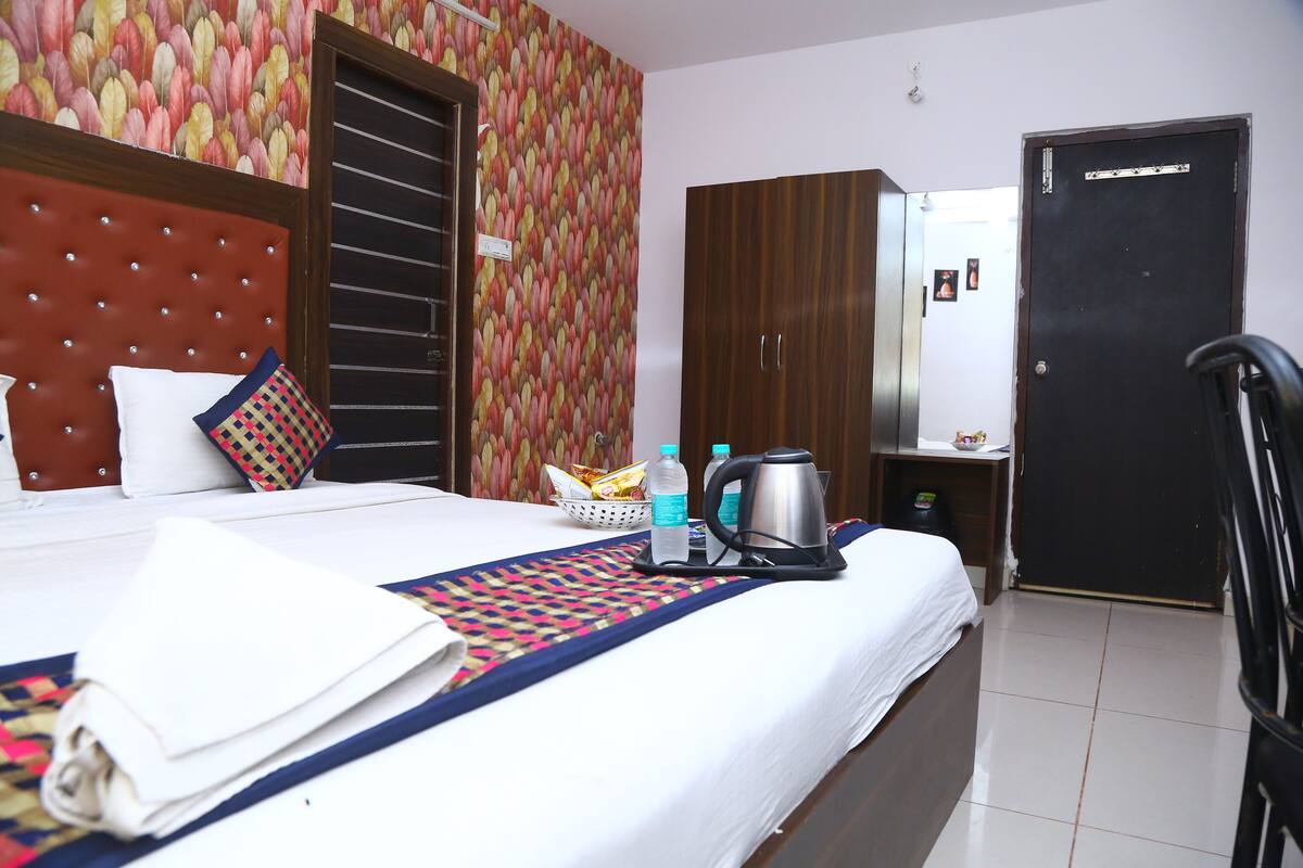 A hotel room with a bed, a wardrobe, a mirror, and a door.