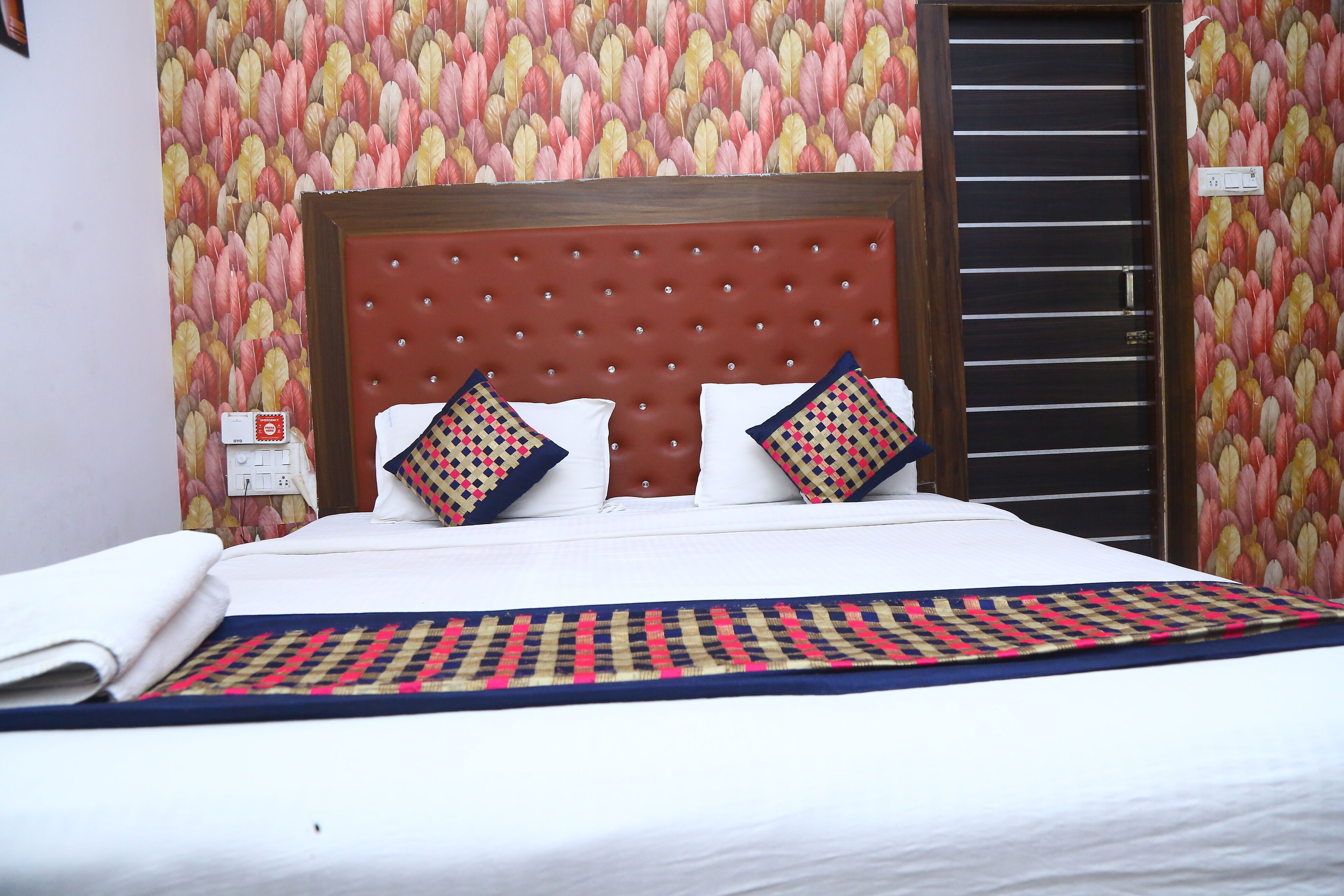 Une chambre d’hôtel avec un grand lit, une tête de lit en bois et un papier peint à motifs.