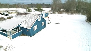 A blue building with a sloped roof, a large garage, and a snow-covered ground.