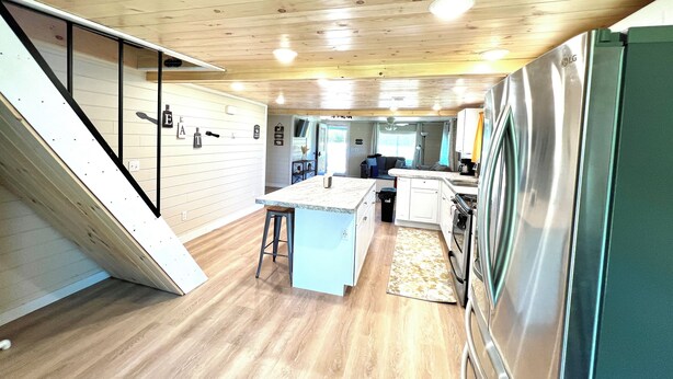 A modern kitchen with wooden floors, a central island, and a built-in refrigerator.