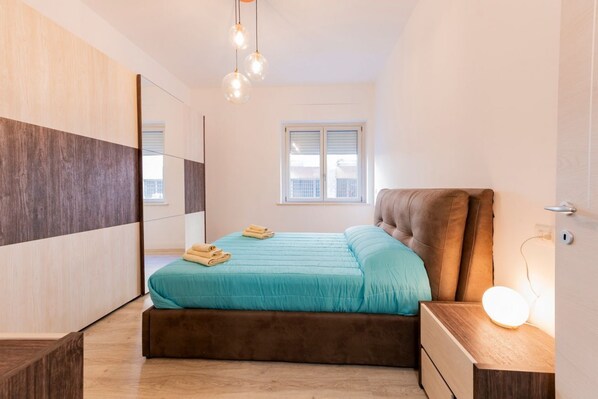 A modern bedroom with a bed, bedside table, and a mirror.