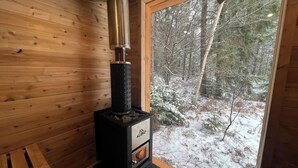 Ein Kaminofen in einer Hütte mit Blick auf einen verschneiten Wald.