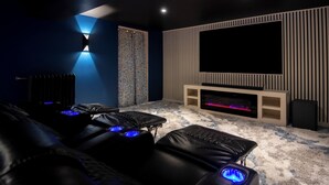 Ein Heimkino mit großem Flachbildfernseher, Ledersessel-Sofas und Teppichboden.