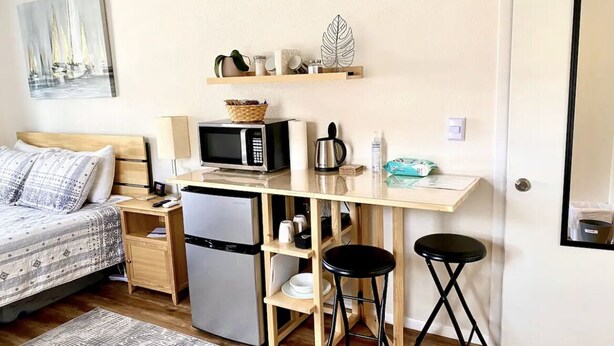 Una habitación compacta con cama, kitchenette y un pequeño espacio para bar.